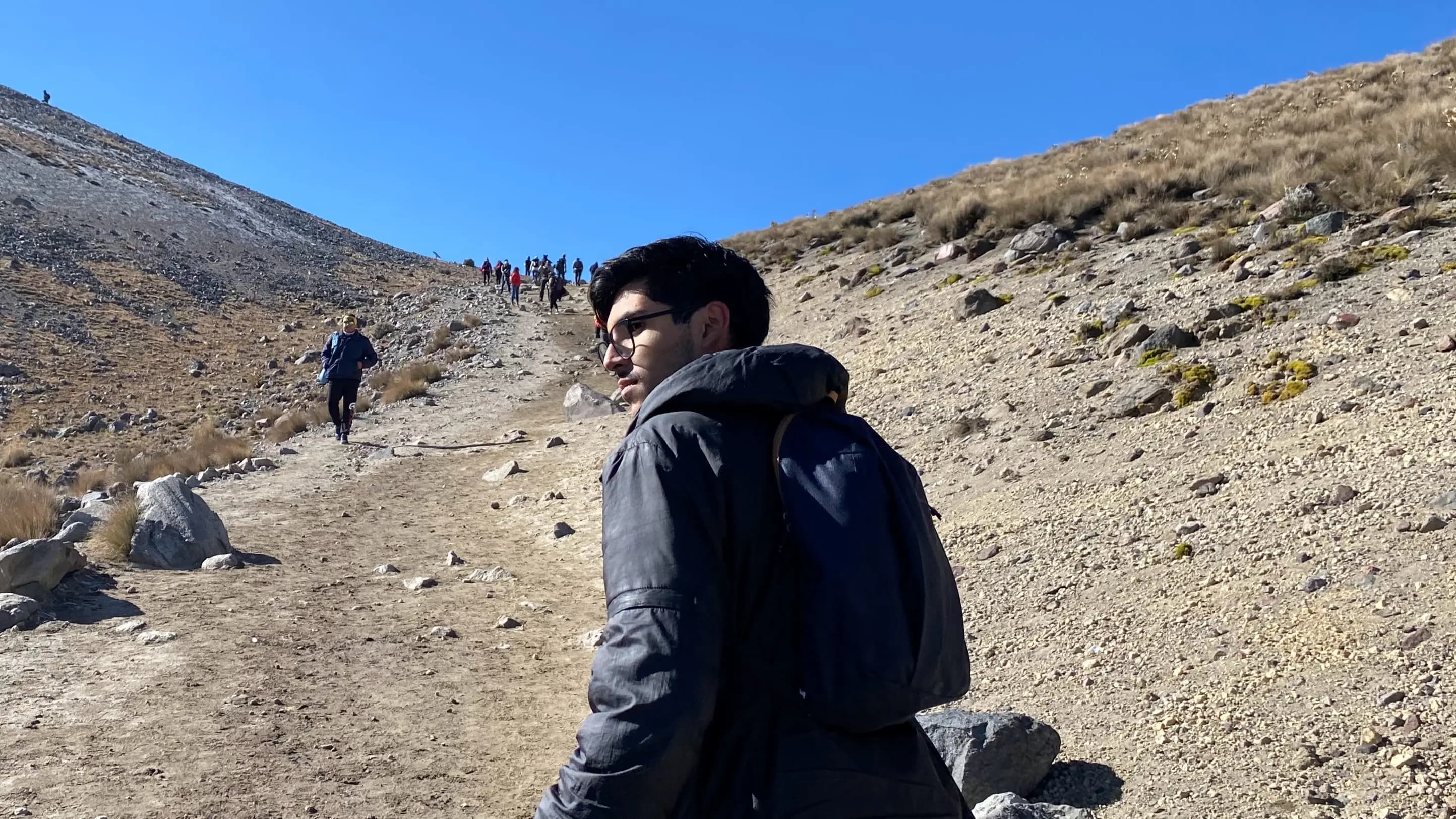 A photograph of me standing on a mountain with my back turned, slightly turned around.